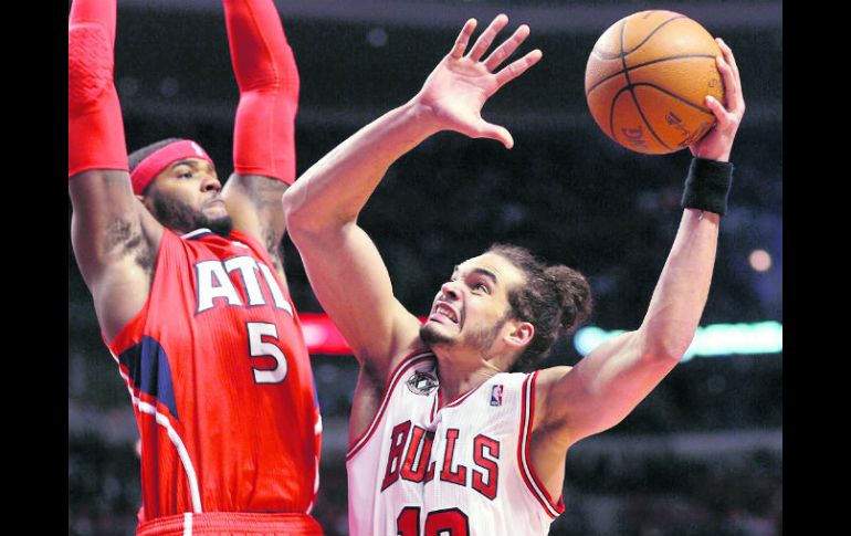 Joakim Noah de los Bulls de Chicago, manda un tiro a la canasta con la marca del jugador de Atlanta, Josh Smith. REUTERS  /