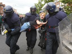 Policías irlandeses someten a una manifestante en Dublin. AP  /