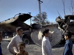 Menores  caminan frente a un camión destruído, una escena común en Pakistán. AP  /