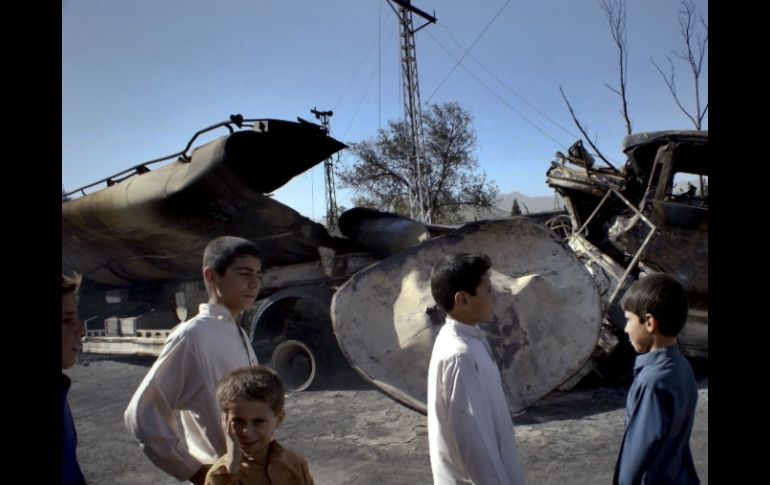 Menores  caminan frente a un camión destruído, una escena común en Pakistán. AP  /