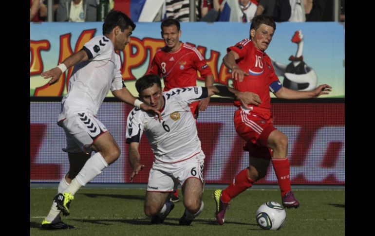 Los jugadores rusos Andrei Arshavin (i) y Roman Pavlyuchenko (c) luchan por el balón con el armenio Henrikh Mkhitaryan. EFE  /