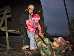 Un soldado ayuda a una niña durante la acción preventiva en los alrededores del complejo volcánico. AP  /