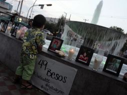 Un niño se acerca a la fuente donde se colocaron velas y las fotos de los fallecidos en la guardería ABC.A.HINOJOSA  /