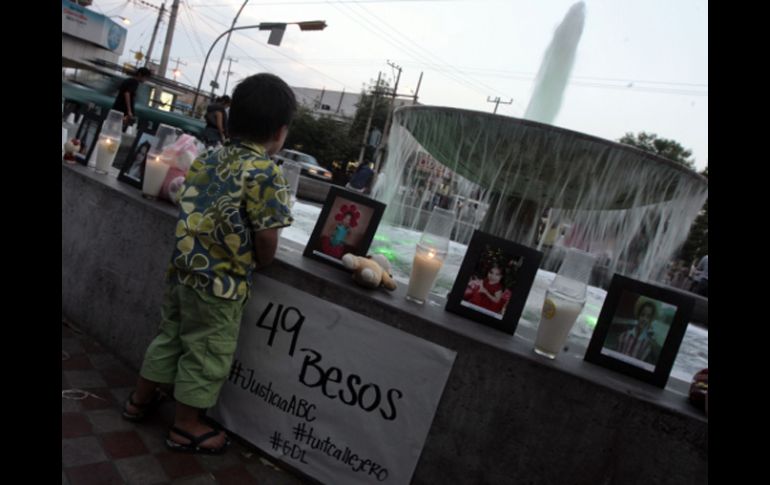 Un niño se acerca a la fuente donde se colocaron velas y las fotos de los fallecidos en la guardería ABC.A.HINOJOSA  /