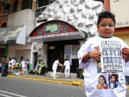 Un niño sostiene un cartel con las imágenes de los presuntos responsables de las muertes de nueve jóvenes en la discoteca. EL UNIVERSAL  /