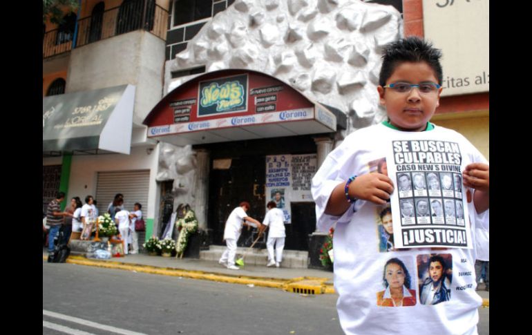 Un niño sostiene un cartel con las imágenes de los presuntos responsables de las muertes de nueve jóvenes en la discoteca. EL UNIVERSAL  /