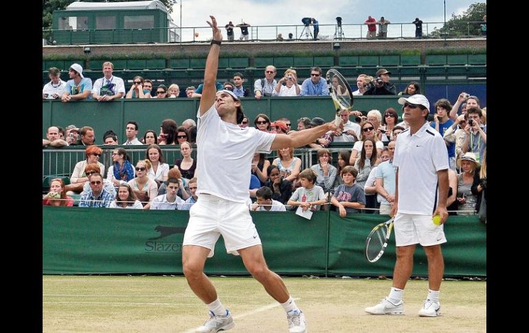 El actual campeón de Wimbledon, Rafael Nadal, ejecuta su servicio ante la mirada de su tío y entrenador, Toni Nadal, durante una prácti  /