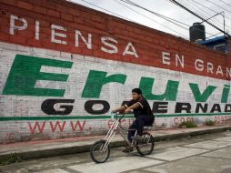 Un niño pasea en bicicleta en Toluca, frente un muro con propaganda del candidato Eruviel Ávila. AP  /