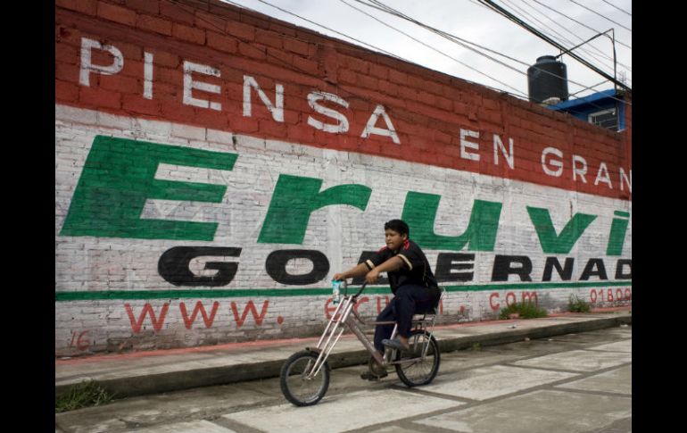 Un niño pasea en bicicleta en Toluca, frente un muro con propaganda del candidato Eruviel Ávila. AP  /