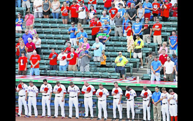 Jugadores de los Rangers de Texas guardan un minuto de silencio por la muerte de Shannon Stone, un fanático que murió el jueves. AP  /