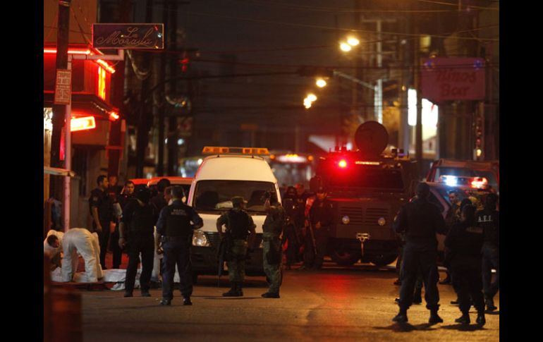 Elementos forenses levantan un cuerpo en la escena del crimen, resguardada por elementos de la Policía Federal y del Ejército. REUTERS  /