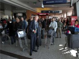 Pasajeros observan las pantallas donde informan sobre la reprogramación o suspensión de sus vuelos en Buenos Aires. EFE  /