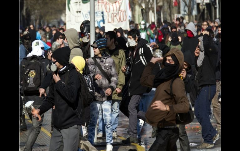 Estudiantes lanzan piedras contra la policía antidisturbios durante una protesta contra el gobierno de Sebastián Piñera. AFP  /