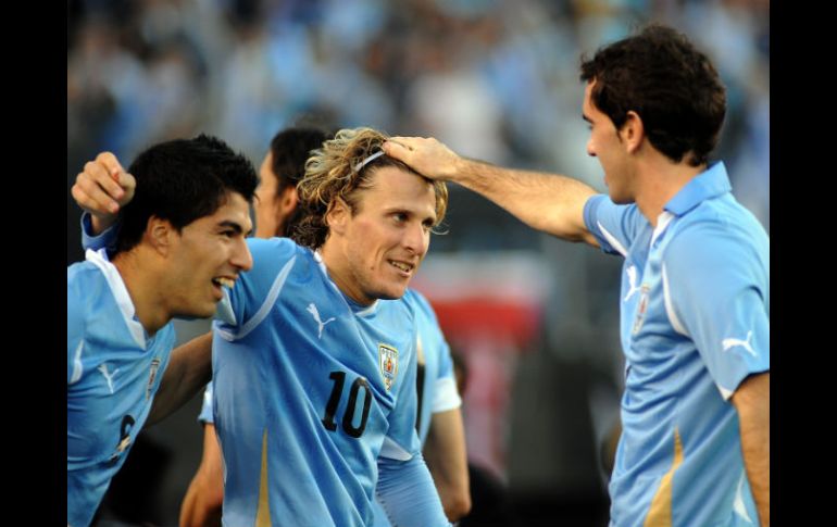 Diego Forlán (C) celebrando el tercer gol de Uruguay con sus compañeros Diego Rodin (D) y Luis Suárez. AFP  /