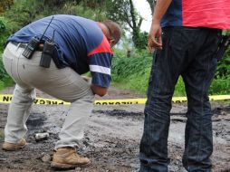 Autoridades analizan el área donde fue abandonada la camioneta blanca con los cuerpos dentro de bolsas y costales. O. RUVALCABA  /