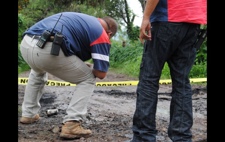 Autoridades analizan el área donde fue abandonada la camioneta blanca con los cuerpos dentro de bolsas y costales. O. RUVALCABA  /