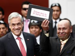 Sebastián Piñera sonríe mientras uno de los mineros sostiene la nota que reveló al mundo exterior que habían sobrevivido. EFE  /