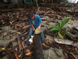 Un niño corta un coco en medio de los escombros tras el paso del huracán “Irene” por Nagua, en República Dominicana. EFE  /