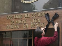 Un hombre coloca un moño negro como señal de luto en el edificio de Gobierno de Nuevo León. REUTERS  /