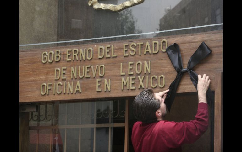 Un hombre coloca un moño negro como señal de luto en el edificio de Gobierno de Nuevo León. REUTERS  /