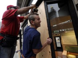 Unos trabajadores colocan tablones en su tienda para protegerse de la llegada de Irene. EFE  /