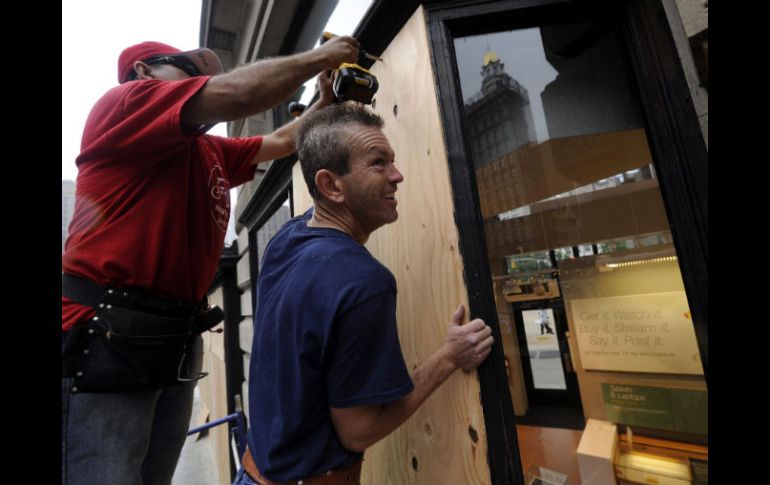 Unos trabajadores colocan tablones en su tienda para protegerse de la llegada de Irene. EFE  /