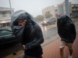 Dos hombres usan bolsas para protegerse de la lluvia que causa ''Irene'' en Virginia. AFP  /