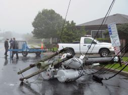 Unos policías aseguran el perímetro en una calle en la que se cayeron varios postes de la luz por efecto del huracán Irene. EFE  /