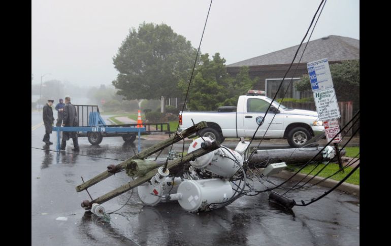 Unos policías aseguran el perímetro en una calle en la que se cayeron varios postes de la luz por efecto del huracán Irene. EFE  /