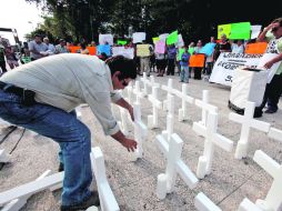 Un regiomontano coloca velas en las 52 cruces que  recuerdan a las víctimas del incendio en el Casino Royale. EL UNIVERSAL  /