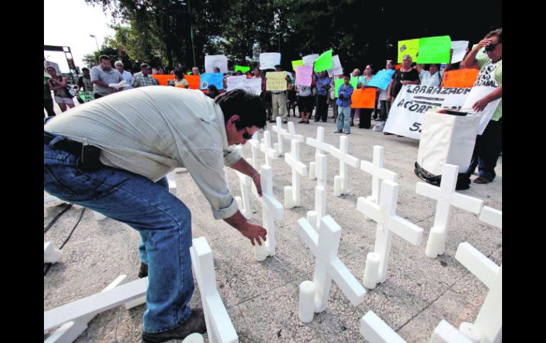 Un regiomontano coloca velas en las 52 cruces que  recuerdan a las víctimas del incendio en el Casino Royale. EL UNIVERSAL  /