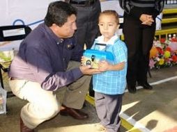 El secretario de educación, Antonio Gloria Morales, entrega personalmente una lonchera a un niño. ESPECIAL.  /