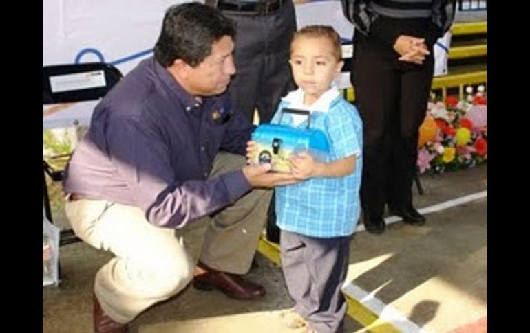 El secretario de educación, Antonio Gloria Morales, entrega personalmente una lonchera a un niño. ESPECIAL.  /