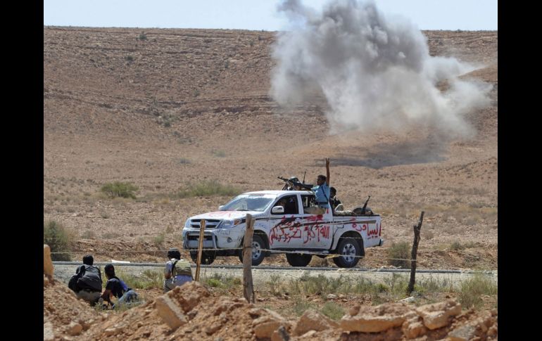 Un cohete lanzado por los leales a Gadhafi explota lejos de un vehículo rebelde. EFE  /