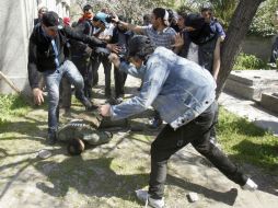 Personas tratan de ayudar a un policía anti disturbios después de que fuera golpeado por manifestantes, en Santiago. REUTERS  /