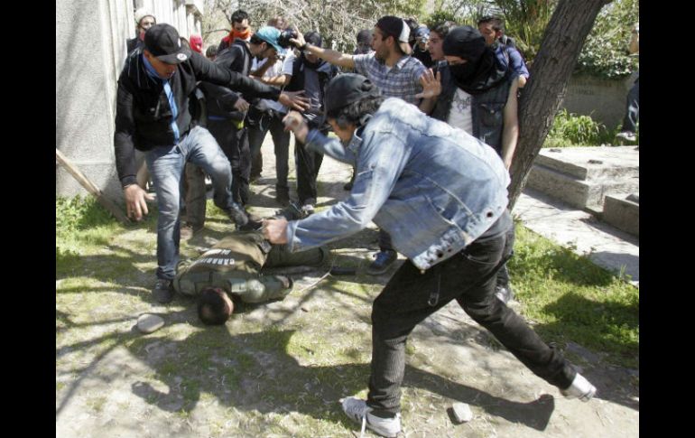 Personas tratan de ayudar a un policía anti disturbios después de que fuera golpeado por manifestantes, en Santiago. REUTERS  /