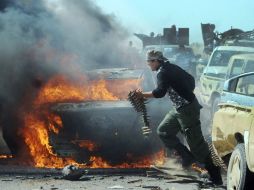 Combatientes rebeldes recuperan armas y municiones de un vehículo de leales a Gadhafi. EFE  /