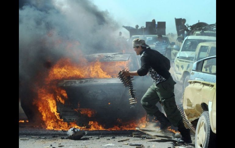 Combatientes rebeldes recuperan armas y municiones de un vehículo de leales a Gadhafi. EFE  /