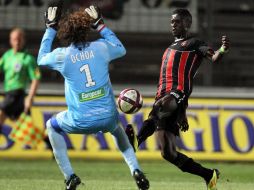 Eric Mouloungui (D) lanza un disparo justo a la cancha donde Guillermo Ochoa ejecuta una maniobra para cuidar que no pase. AFP  /