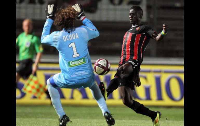 Eric Mouloungui (D) lanza un disparo justo a la cancha donde Guillermo Ochoa ejecuta una maniobra para cuidar que no pase. AFP  /