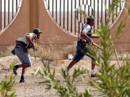 Rebeldes libios corren para ponerse a salvo de los disparos de los fieles a Gadhafi, durante un combate en Bani Walid. EFE  /