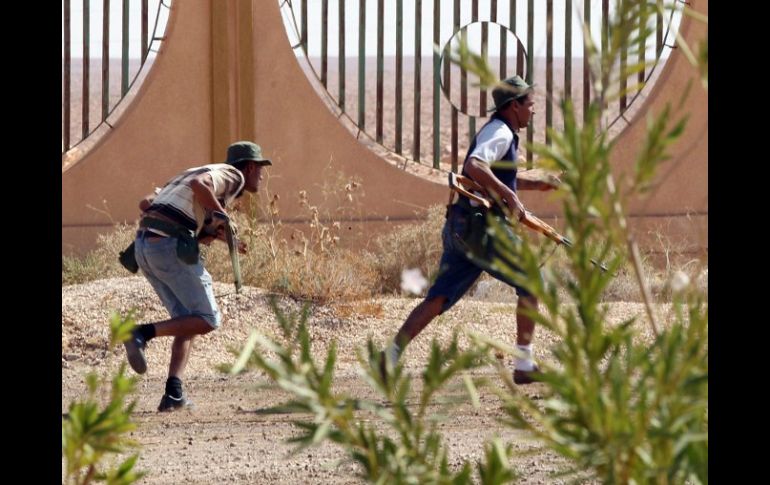 Rebeldes libios corren para ponerse a salvo de los disparos de los fieles a Gadhafi, durante un combate en Bani Walid. EFE  /