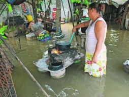 Una mujer prepara sus alimentos al interior de su casa inundada debido al desbordamiento del Río La Sierra, en Tabasco. EFE  /