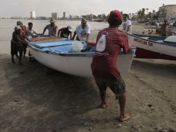 Pescadores ponen en resguardo sus lanchas ante la amenaza del fuerte oleaje. EFE  /