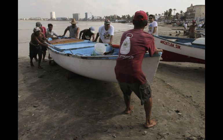 Pescadores ponen en resguardo sus lanchas ante la amenaza del fuerte oleaje. EFE  /