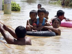 Niños atraviesan en flotadores una de las zonas inundadas en la población. EFE  /