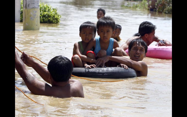 Niños atraviesan en flotadores una de las zonas inundadas en la población. EFE  /