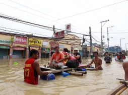 Filipinos atraviesan una de las zonas inundadas tras el paso del tifón Nalgae. EFE  /