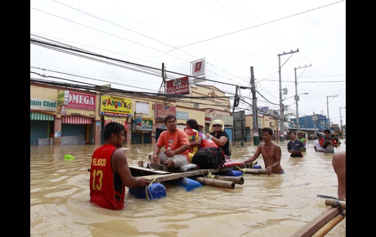 Filipinos atraviesan una de las zonas inundadas tras el paso del tifón Nalgae. EFE  /