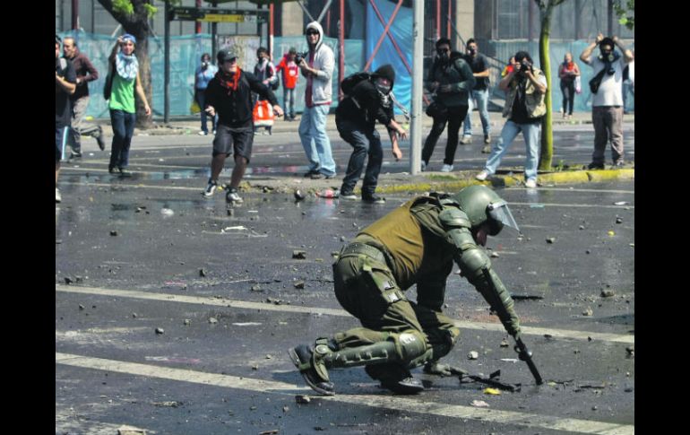 Manifestantes se enfrentan a pedradas con la Policía. Un oficial permanece en el piso, en Santiago de Chile. EFE  /